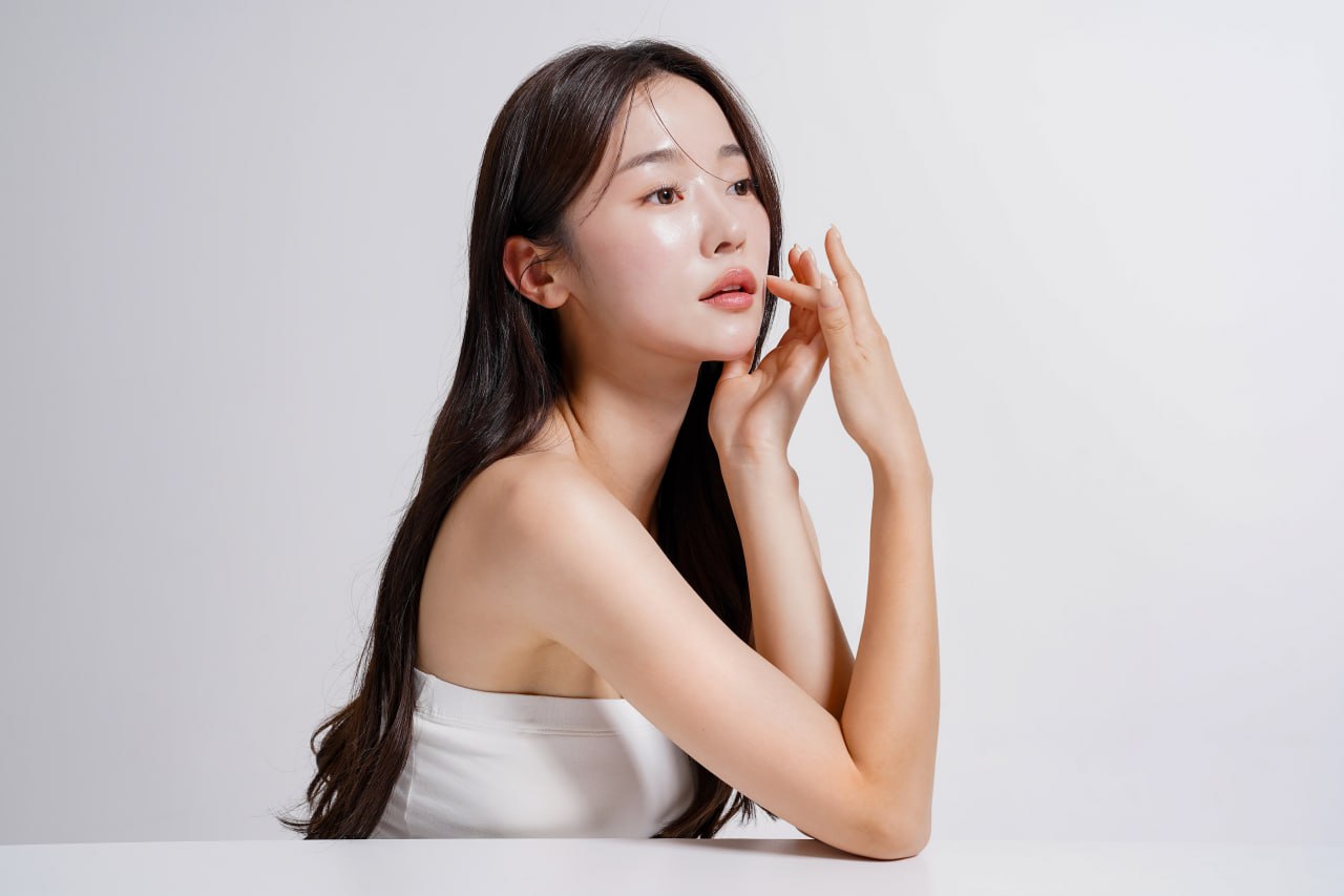 Young woman with glowing, camera-ready skin posed in profile touching her cheek to illustrate Celebrity facial treatment