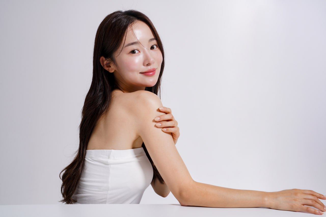 Young woman with glowing, camera-ready skin smiling over her shoulder showcasing smooth complexion for Celebrity treatment