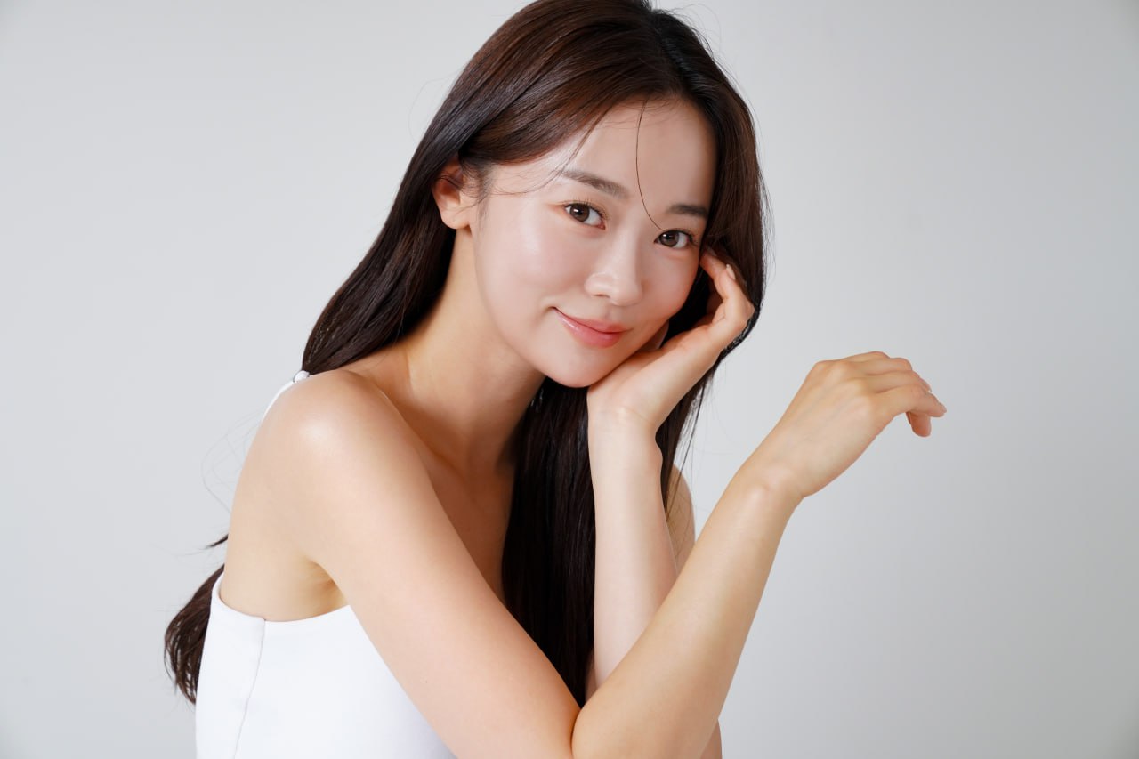 Smiling woman with dewy, glowing skin resting her face on her hand showcasing Daily Glow facial results