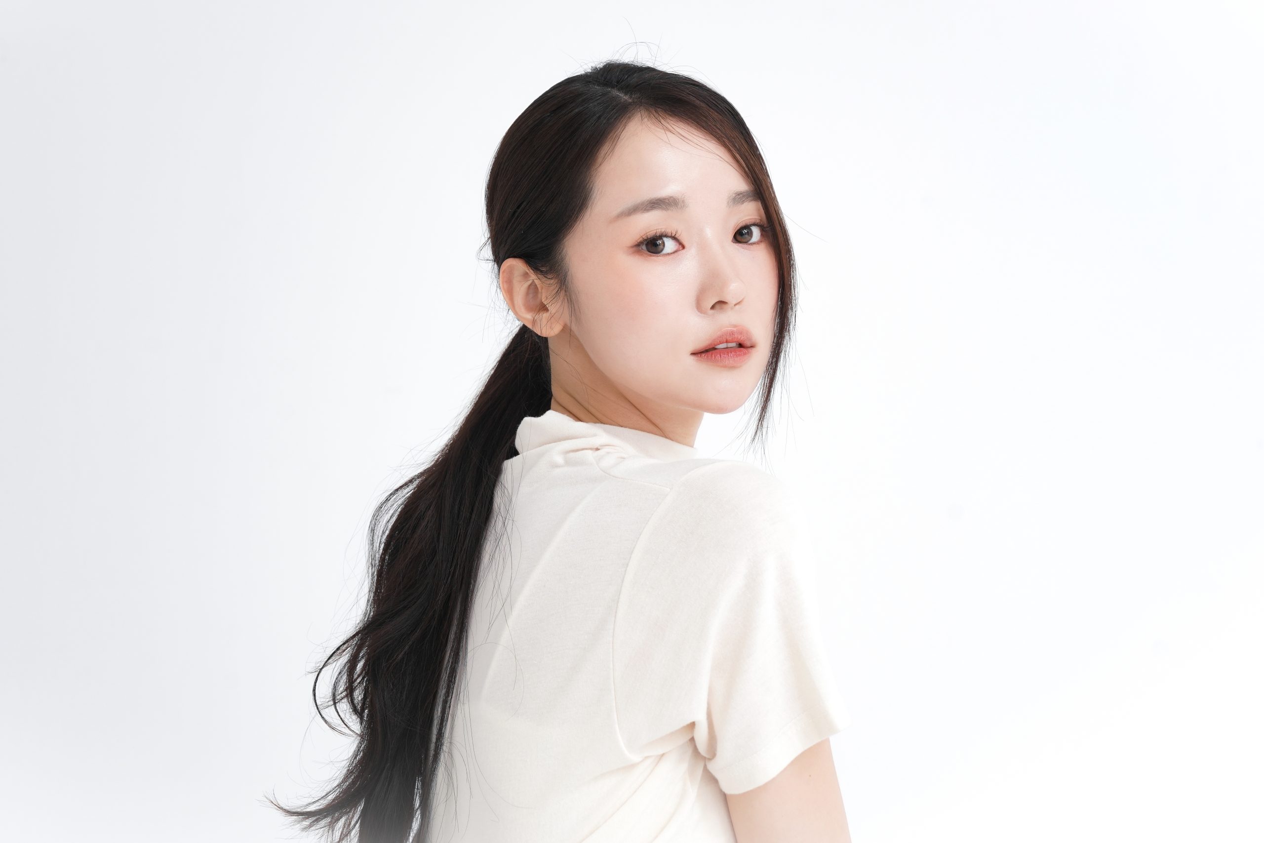 Young woman with clear glowing skin looking over shoulder against white background for peel & fill page