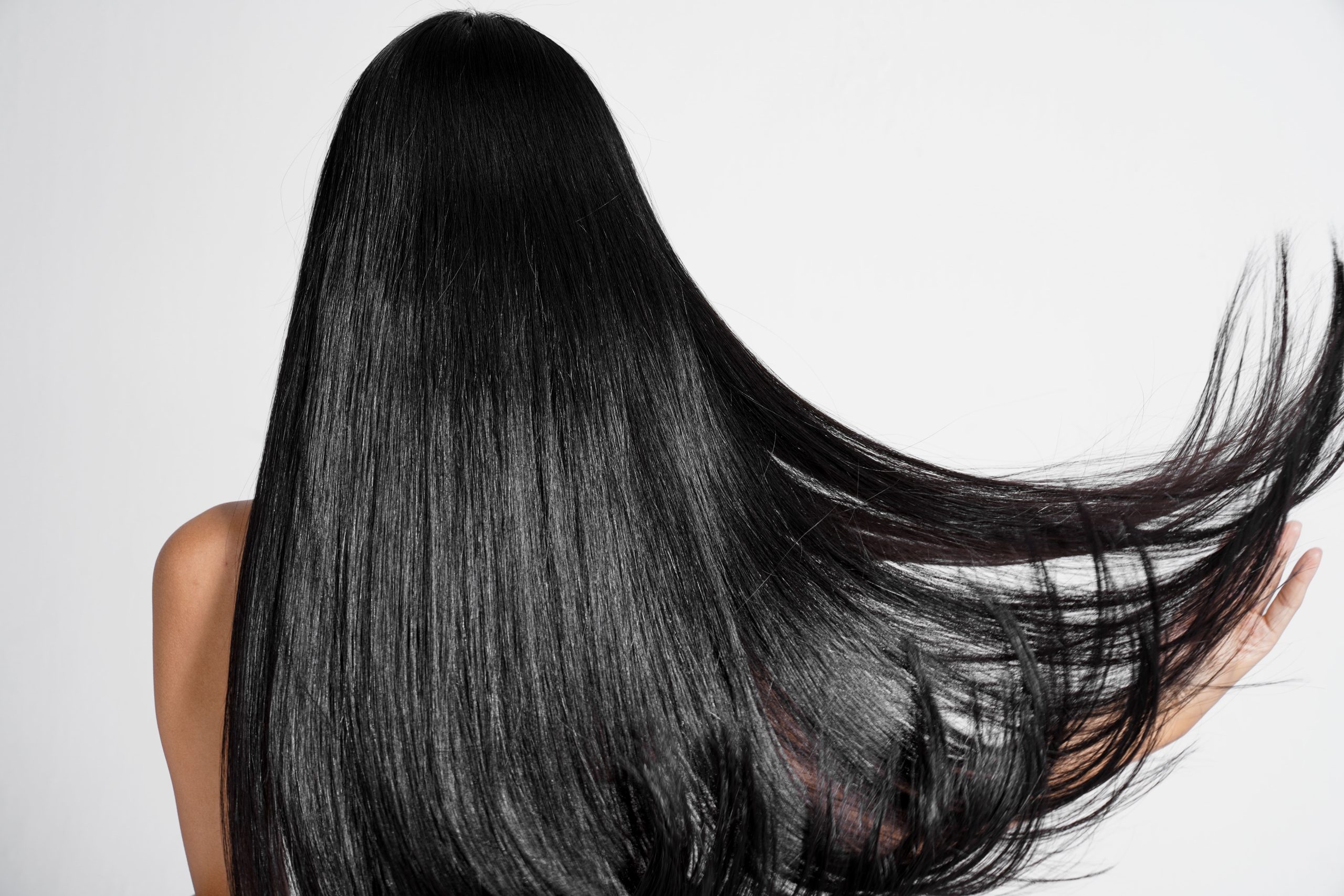 Back view of a patient with long, glossy black hair and healthy scalp for hair regeneration and scalp health program