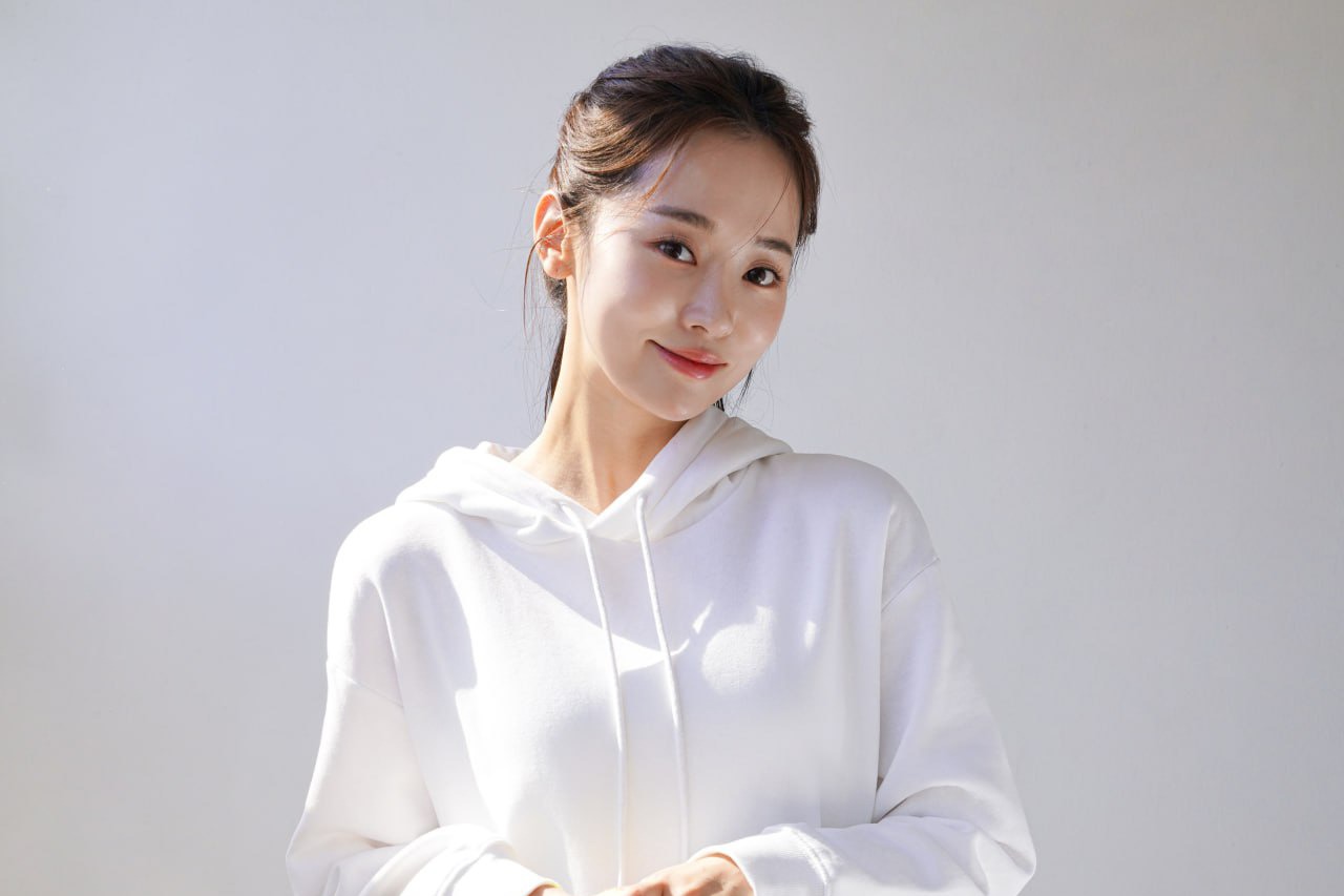 Young woman in white hoodie smiling with clear skin, ideal for sports skincare and post-workout skincare imagery