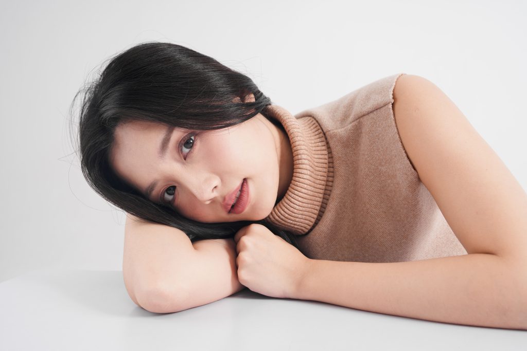 Close-up of a relaxed woman with flawless skin resting her face on her arms, showcasing dewy complexion for VVIP facial care
