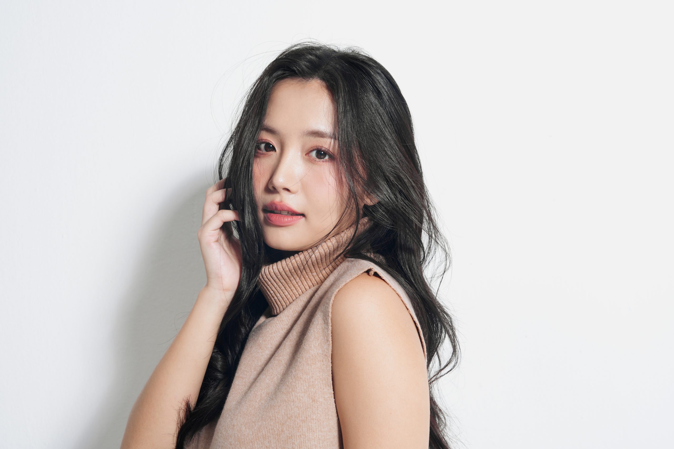 Young Asian woman with flawless skin in a beige turtleneck sleeveless top, portrait for VVIP skin rejuvenation package