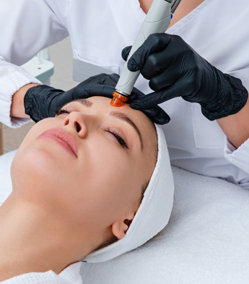 Woman receiving a BB Shine facial treatment with a handheld device applied to forehead by clinician in gloves